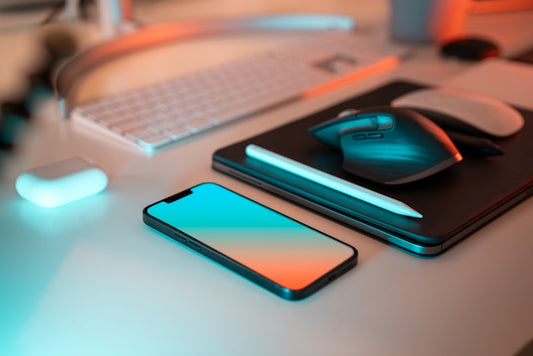Escritorio con celular, mouse y accesorios con iluminacion turquesa y naranja